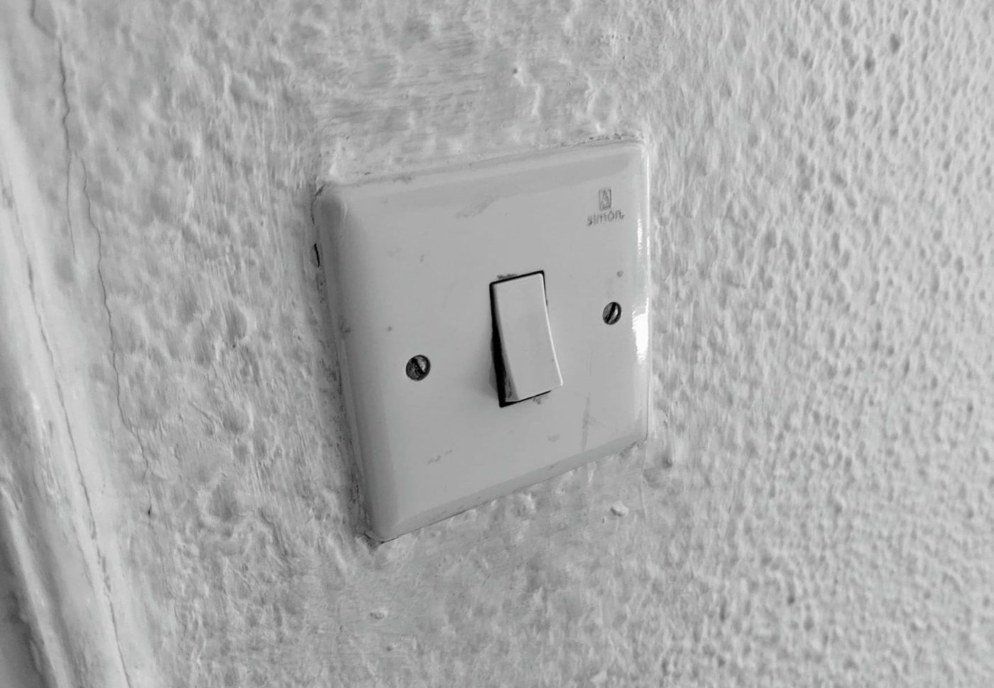 Una pared blanca con un viejo interruptor pulsador